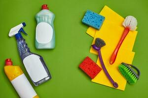 Detergents and cleaning accessories on a green background. Housekeeping concept. photo