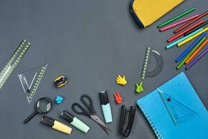 Flat lay photo of workspace desk with school accessories or office supplies on gray background.