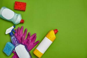 Detergents and cleaning accessories on a green background. Housekeeping concept. photo