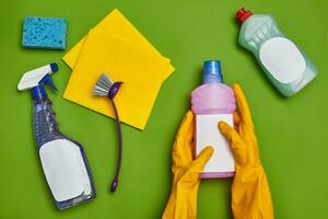 Detergents and cleaning accessories on a green background. Housekeeping concept. photo