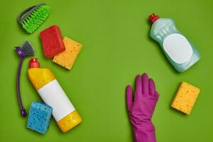 Detergents and cleaning accessories on a green background. Housekeeping concept. photo