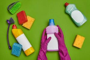 Detergents and cleaning accessories on a green background. Housekeeping concept. photo