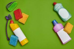 Detergents and cleaning accessories on a green background. Housekeeping concept. photo