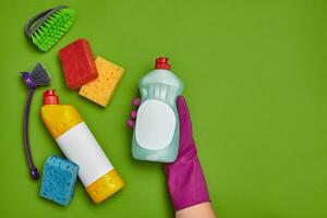 Detergents and cleaning accessories on a green background. Housekeeping concept. photo