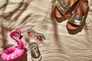 Traveler vacation accessories are laid out on a white beach sand. Flat lay, top view. photo