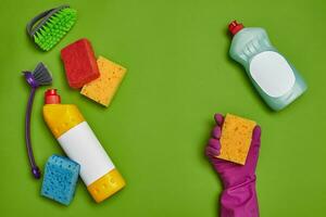 Detergents and cleaning accessories on a green background. Housekeeping concept. photo