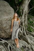 elegante morena mujer en seda gris vestir posando en en el rocas foto
