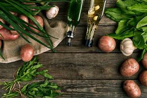 Fresh potatoes, oil, garlic and spicy herbs on a kitchen wooden background. photo