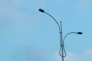 Minimalistic photo of streetlights against a blue sky in the afternoon