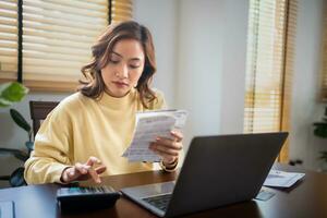 A woman uses a calculator to check the sum of her home expenses and she is stressed over the home expenses. photo