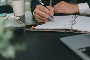 man hands with pen writing on notebook in the office.learning, education and work.writes goals, plans, make to do and wish list on desk. photo