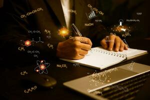 Male hand holding a pen write down scientific data or math formulas at the desk. photo