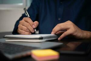 man hands with pen writing on notebook in the office.learning, education and work.writes goals, plans, make to do and wish list on desk. photo