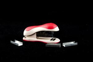 a stapler with a red handle and white paper photo