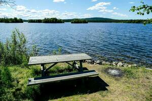 a picnic table sits on the shore of a lake photo