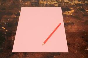 a pink sheet of paper with a red pencil on top photo