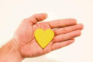 un del hombre mano participación un amarillo corazón conformado pedazo de papel foto