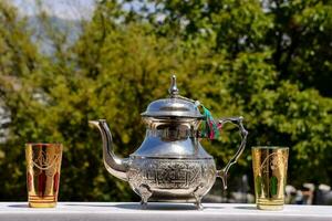 a silver tea pot and two gold cups on a table photo