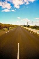 an empty road with a blue sky and clouds photo