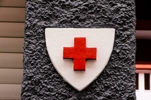 a red cross on a white shield on a building photo