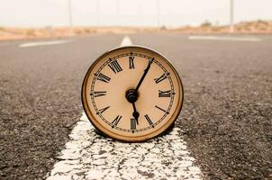 a clock is sitting on the side of a road photo