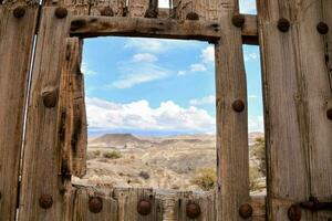 a window in an old wooden building with a view of the desert photo