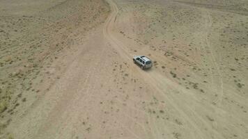 suv auto gaat Aan zanderig woestenij. woestijn landschap en heuvels Aan achtergrond. antenne visie. dar is in een baan om de aarde in de omgeving van. vaststelling schot video