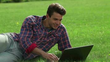 homme mensonge sur herbe à parc avec portable video