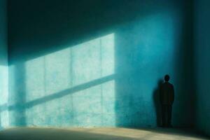 A lonely man stands facing the wall in an empty room. Blue wall with shadows. Concept of human loneliness, social problems. Generative AI photo