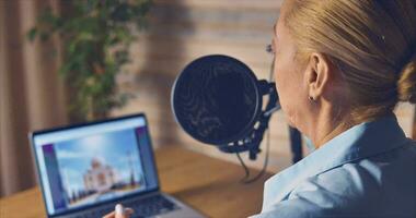 une femme dans une Accueil studio portant une bleu chemise hôtes une podcast. ordinateur et blocs-notes sur le table video