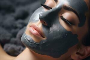 Close up of a womans face applying a charcoal detox facial mask relaxing spa background with empty space for text photo