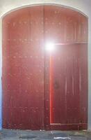 Old shabby ajar wooden door in the wall of the house photo