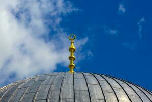 Decorated roof of an ancient mosque against a blue sky with clouds photo