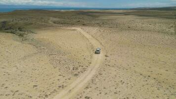 suv carro vai em arenoso terreno baldio. Alto altitude tomada. aéreo visualizar. zangão é Segue carro video