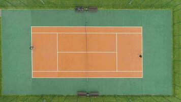 Players are playing tennis on court. Aerial vertical top view. Drone is flying up. video