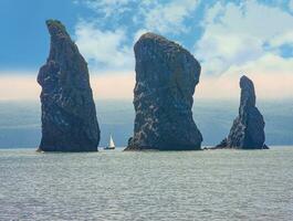 Sailboat sails near the coast and rocks on Kamchatka Peninsula photo