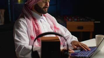 Smilling arab man doing online shopping, using computer to look up tech products to buy. Middle Eastern person adding credit card payment method on secure website, ordering with instant delivery video