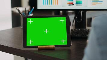 opstarten specialist looks Bij digitaal tablet met groene scherm, gebruik makend van apparaatje met blanco Chroma sleutel sjabloon. persoon werken Bij bureau met geïsoleerd mockup kopieerruimte, controle afzet gegevens. dichtbij omhoog. video