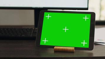 Empty desk with greenscreen on tablet in business coworking space, isolated copyspace layout on modern gadget display. Workstation with device showing chromakey mockup screen. video