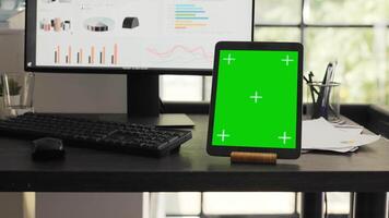 Desk with greenscreen on modern tablet in business coworking space, showing isolated chromakey layout design on mobile gadget display. Empty office workstation running device with copyspace. video