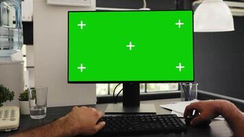 POV of young man at office desk checking greenscreen and isolated chromakey template, solving business operations. Manager sitting at desk looking at blank mockup display. Tripod shot. video