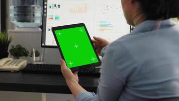 Office worker examines greenscreen layout in coworking space, working on business operations and looking at isolated chromakey display. Woman holding tablet with blank copyspace. video