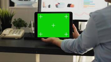 vrouw controle groene scherm Aan tablet in creatief agentschap coworking ruimte, op zoek Bij Chroma sleutel Scherm met geïsoleerd mockup Aan mobiel apparaatje indeling. werknemer Holding mockup apparaat. video