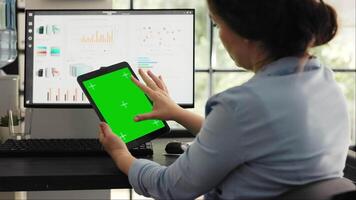 Specialist checking blank greenscreen template in coworking space, working on startup office tasks and looking at isolated copyspace display. Woman holding tablet with blank chromakey. video