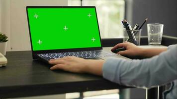Woman analyst works on laptop with greenscreen isolated display, checking pc with blank mockup template. Young person working on business tasks using chromakey copyspace screen. video