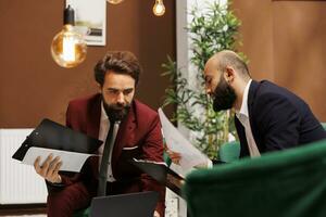 Male travellers attending meeting abroad to share experiences, discovering new corporate perspectives and ways of doing business. Colleagues in suits exchanging cultural ideas in hotel. photo