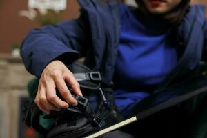 Close up shot of tourist securing snowboarding gear in hotel foyer, prepared for winter vacation at ski resort. Detailed view of person inspecting a snowboard, getting ready for snowy adventure. photo