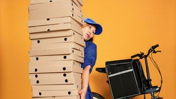 cansado mensajero agobiado por enorme pila de pizza, esperando para cliente a responder puerta. agotado bicicleta jinete aislado terminado estudio antecedentes entregando grande comida orden a negocio foto