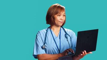 Nurse imputing medical checkup data on notebook, unhappy with dissapointing patient health results. Healthcare professionist isolated over studio background scheduling future appointment photo