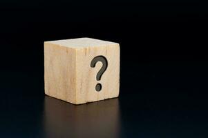 Question mark engraved on wooden cube with dark background. Question and Answer session. photo